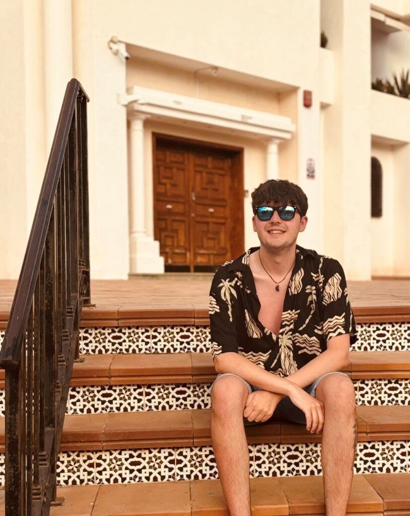 Image of Jack sitting on steps wearing sunglasses, looking relaxed.