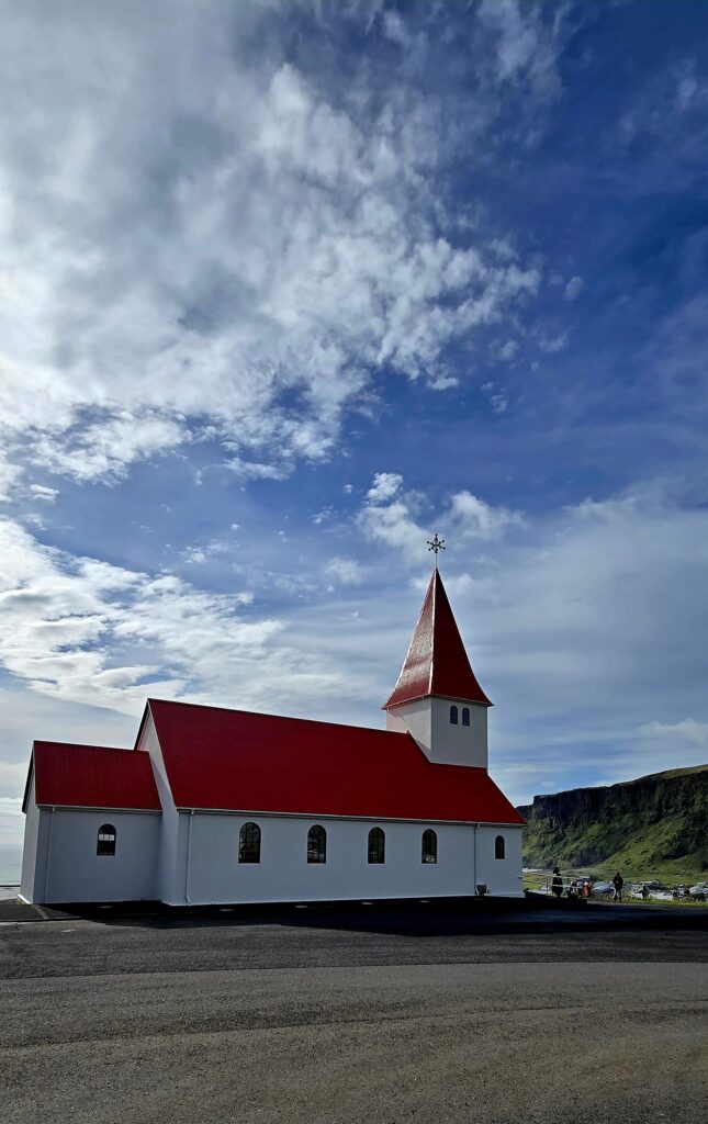 The church with white walls and a striking red roof at Vik i Myrdal Church, Vik