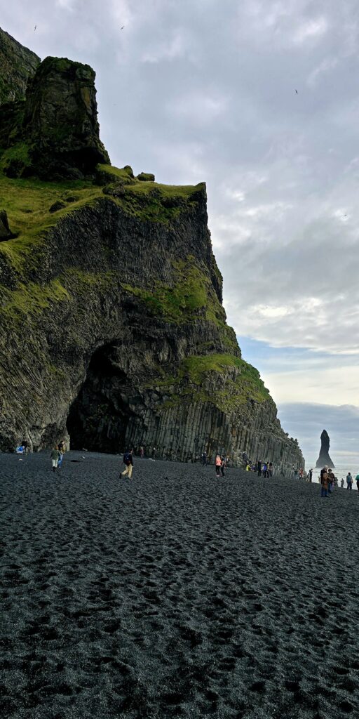 Reynisfjara Beach is a beach with black sand and cliff faces with erosion so you can see the geology of the lave layers and the columns.