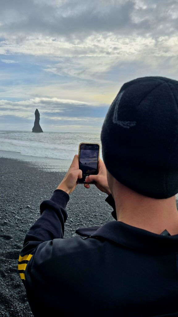 My son taking a photograph of the stacks left behind in the sea at the edge of the Reynisfjara Beach