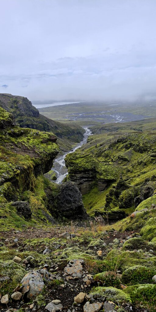 Mulagljufur Canyon - a deeply green and misty photo of the canyon and rock formations with a waterfall