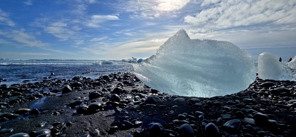 piece of glacier with a bright blue sky sitting on Black Diamond Beach