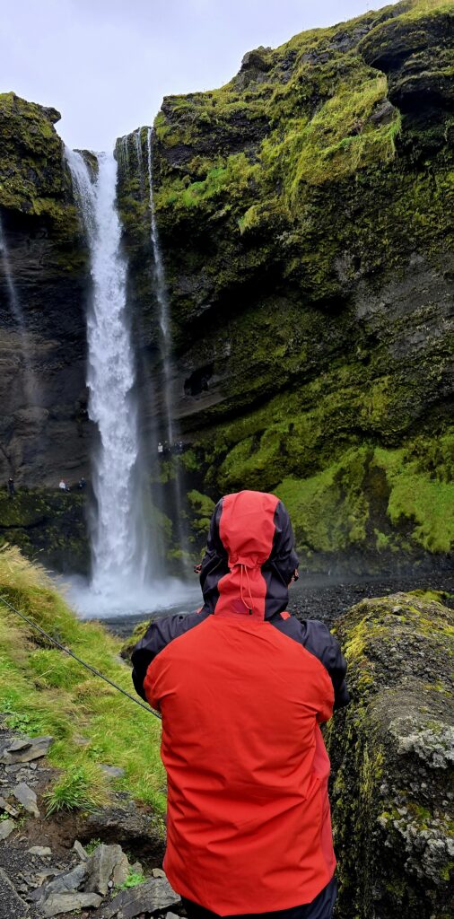 My son, in a bright orange coat looking at the Kvernoss Waterfall