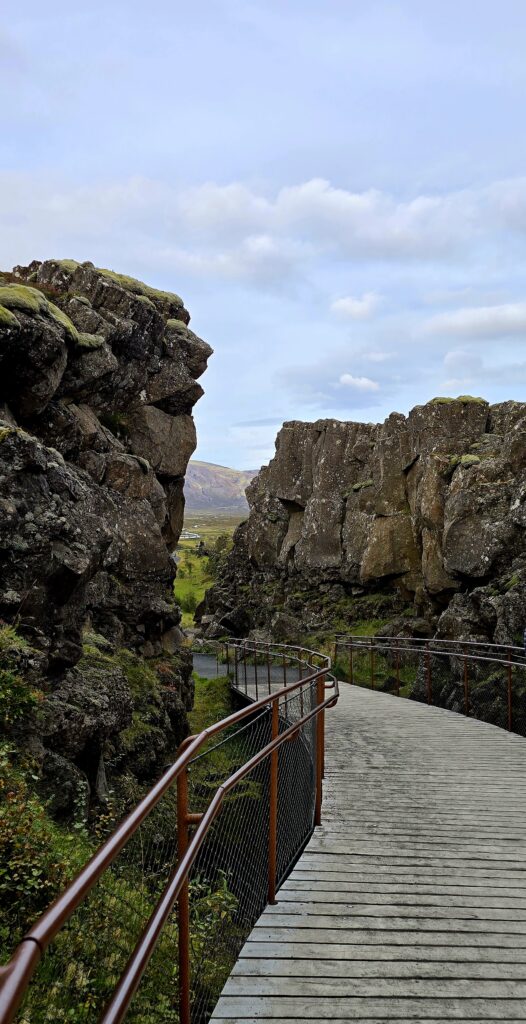 The path runs between two cliffs. The cliffs are the fault line between two continental plates at Thngvellir National Park