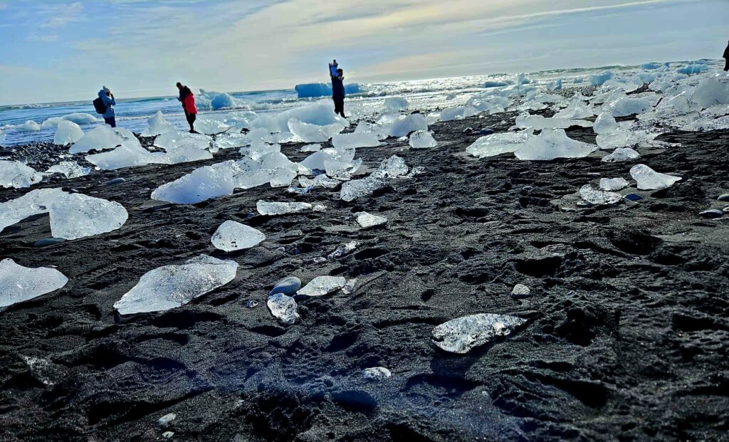 Broken glaciers spread across the black sand at Black Diamond Beach.