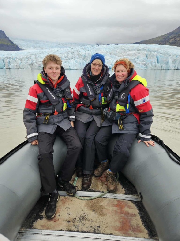Family photo on the front of the oat wih a blue/ white glacier behind at Fjallsarlon